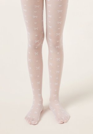 Kinderbeine, die durchsichtige weiße Strumpfhosen mit kleinen Herz- und Schleifenmustern tragen, stehen auf einer hellen Oberfläche.