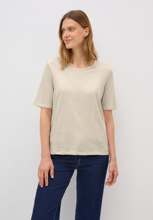 Beige short-sleeve t-shirt in a soft, lightweight fabric with a crew neckline, paired with dark blue jeans. Simple, relaxed fit.