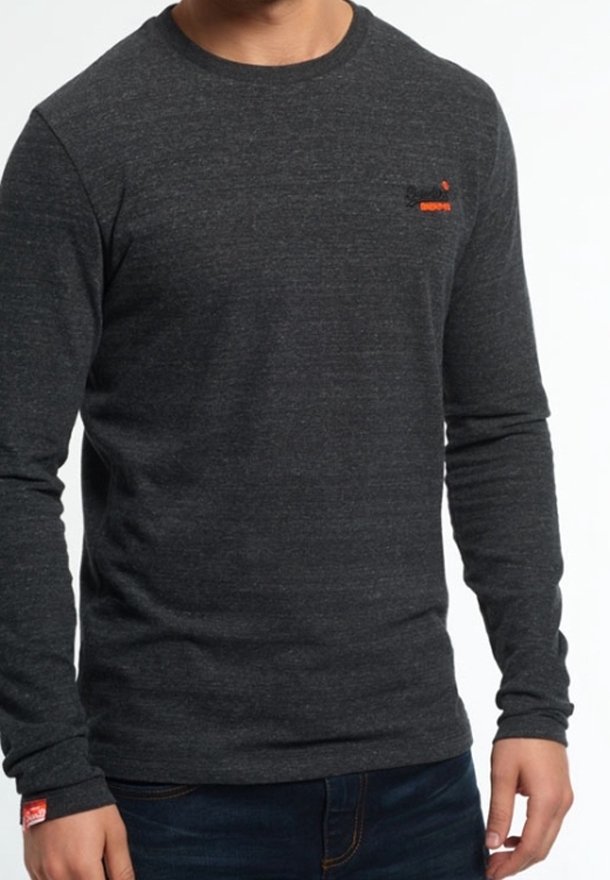 Pitkähihaisesta harmaasta T-paidasta, joka on valmistettu teksturoidusta materiaalista. Paidassa on pieni punainen graafinen logo rinnassa ja pyöreä pääntie.