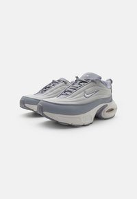 Sivi in svetlo sivi športni copati z mrežnim zgornjim delom, oblazinjenim ovratnikom in vidnim zračnim podplatom. Na strani je značilni Nike logotip.