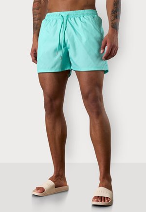 Türkise Badeshorts aus leichtem Stoff mit einem elastischen Bund und einem Kordelzug, versehen mit einem dezenten geprägten Muster.