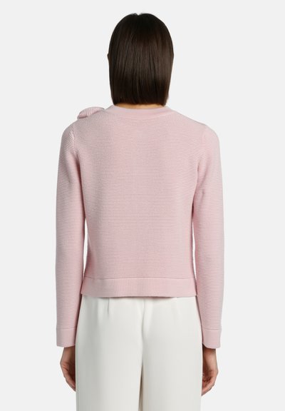 Svetlo roza pletena majica z raznoliko tkanino, rebrastimi manšetami in subtilnim detajlom na rami, končana s skrajšanim robom.