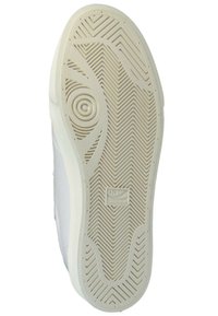 White sneaker sole with a textured, herringbone pattern. Notable logo detail and circular designs, emphasizing grip and traction features.