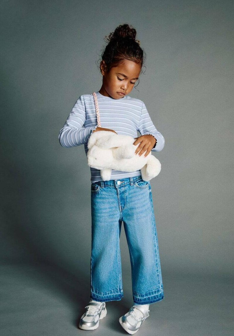 Svetlo modra prugaasta srajca z dolgimi rokavi, preveliki modri kavbojke, bela mehka torbica, srebrni športni copati. Enostavni vzorci in sproščen kroj.