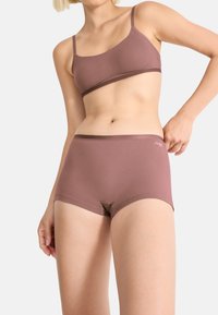 Sæt med bh og shorts i jordfarvet brun. Blødt, sømløst stof med en glat tekstur. Har tynde stropper og elastisk taljebånd.