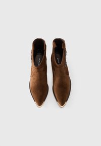 Pair of brown suede pointed-toe ankle boots with black soles and metallic toe caps, viewed from above on a white background.