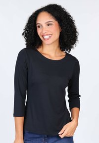 Black, long-sleeve top with a round neckline; made from a smooth, stretchy fabric. Features a slim fit and slightly curved hem.