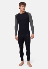 Long-sleeve thermal top in black with gray sleeves; fitted design. Paired with black thermal leggings. Soft, stretchable fabric.