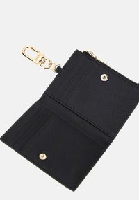 Portafoglio nero realizzato in materiale testurizzato, con clip dorata, chiusura a zip e diversi scomparti per schede all'interno. Design minimalista senza decorazioni.