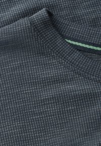 Dark blue, ribbed fabric with a textured surface. Features a rounded neckline and a green accent detail near the collar.