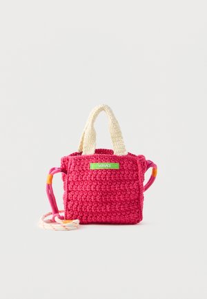 Pequeño bolso rosa de ganchillo con asas crema, correa larga multicolor y etiqueta verde de Versace en el frente.