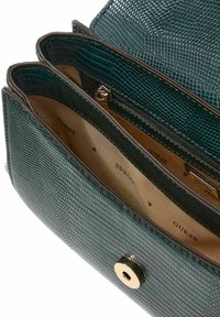 Sac à main en simili cuir vert avec extérieur texturé, ferrures dorées et trois compartiments, dont une section zippée. Intérieur doublé.