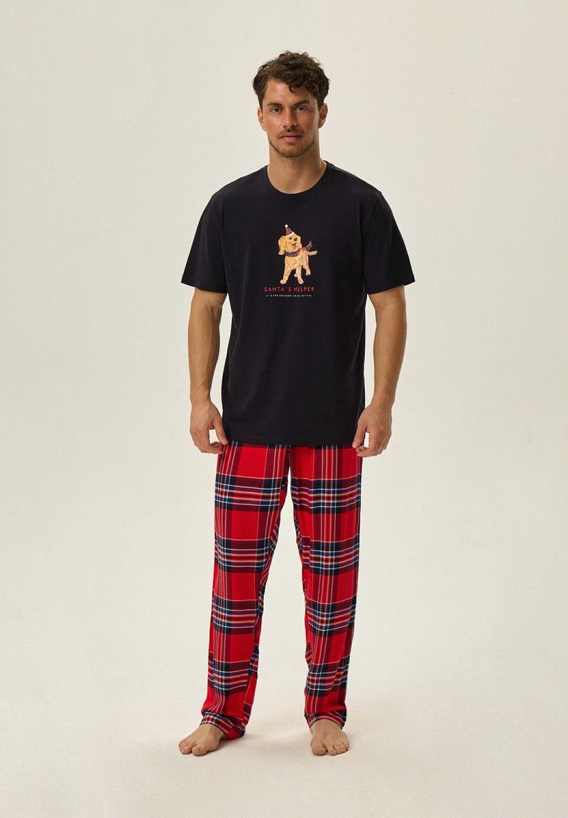 Koszulka z krótkim rękawem w kolorze granatowym z grafiką psa, zestawiona z czerwonymi spodniami dresowymi w kratę z czarnymi i niebieskimi akcentami. Miękka tkanina, luźny krój.