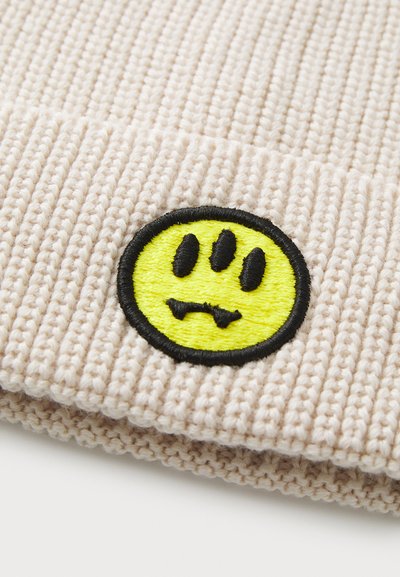 Beanie lavorato a maglia beige con un sorriso giallo ricamato di forma rotonda con dettagli neri e un design rigato testurizzato.