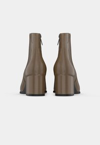 Braune synthetische Knöchelstiefel mit glatter Oberfläche, quadratischen Absätzen und Reißverschlussdetails an der Rückseite, die ein elegantes, schlankes Design aufweisen.