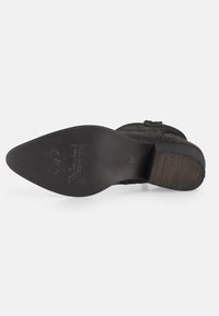 Botte en daim noir avec une semelle en caoutchouc texturée. Dotée d'un bout arrondi et d'un petit talon. Logo gravé et détails de taille au dos.