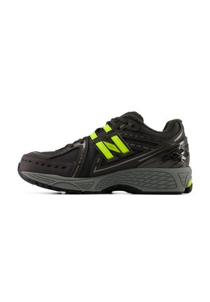 Chaussure de sport noire et grise avec des accents vert vif, semelle épaisse et rembourrée, et design à lacets, vue de côté sur fond blanc.