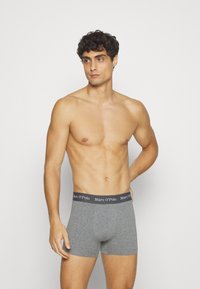 Harmaat puuvillabokserit, joissa on istuva muotoilu ja joustava vyötärö, jossa on musta "Marc O'Polo" -logo. Sujuva kangas, keskivartalon pituinen.