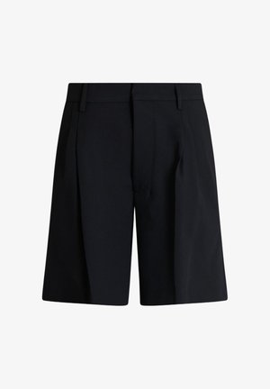 Shorts noirs confectionnés sur mesure, longueur genou, avec passants de ceinture, plis devant et une texture de tissu propre et lisse.