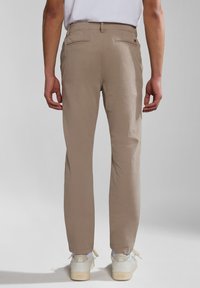 Chino beige in cotone con taglio dritto, due tasche posteriori e finitura pulita, abbinati a sneakers bianche. Nessun motivo o decorazione visibile.