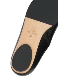 Zapato de cuero negro con un acabado suave. La suela presenta un inserto de cuero beige y un acento de tacón de goma negra redonda. Tamaño 37 marcado en el interior.