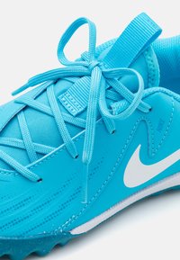 Helle blaue Sportschuh mit strukturierter Oberseite, ausgestattet mit einem weißen Nike-Logo und passenden Schnürsenkeln. Abgerundete Zehenpartie und Gummisohle für besseren Halt.