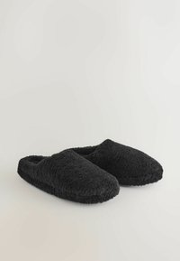 Papuci din pluș negri, cu vârf rotund, textură moale și un design cu spate deschis pentru a fi ușor de încălțat și descălțat.
