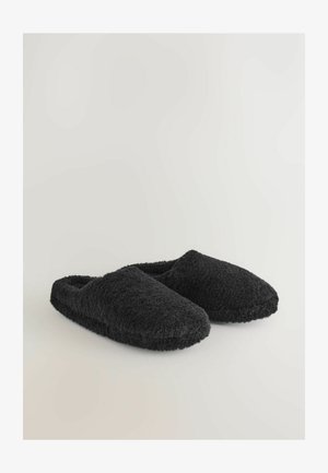 Sorte fløjls slippers med rund tå, blød tekstur og åben bagdesign for nem på- og aftagning.