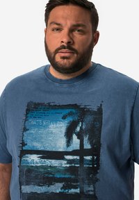 Modré bavlněné tričko s kulatým výstřihem, s grafickým potiskem palem a oceánských vln ve tmavších odstínech, se překryvným textem.