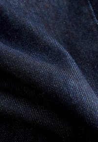 Tissu en denim bleu foncé avec une texture lisse et un éclat subtil, présentant un tissage sergé classique et de fines coutures.