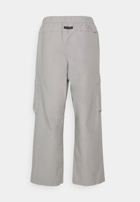 Světlé šedé volné cargo kalhoty s elastickým pasem a kapsami s klopou na bocích, štítek Nike Air na zadním pasu.