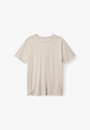 Käytännöllinen, vaaleanbeige lyhythihainen t-paita, joka on valmistettu pehmeästä, teksturoidusta kankaasta. Paidan kaula-aukko on pyöreä ja helman muotoilu on epätasainen. Ei näkyvää brändäystä.