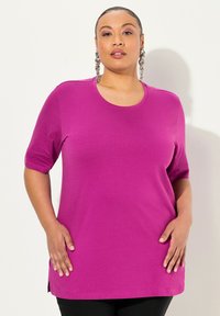 T-shirt fucsia a maniche corte in morbido tessuto con scollatura rotonda e spacchi laterali, vestibilità comoda, senza motivi o accenti visibili.