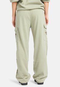 Lichtgroene cargobroek van fleece, met zijzakken en geborduurde accenten, in een losse, ontspannen pasvorm. Gevoerde stof.