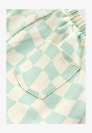 Piparmētru zaļš un krēms pārbaudīts audums ar teksturētu virsmu. Iespējota viena aizmugures kabata ar šuvju apdari. Elastīga jostasvieta.