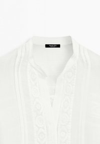 Wit overhemd met een opstaande kraag en verticale geborduurde kanten panelen langs de vooropening, gelabeld Massimo Dutti.