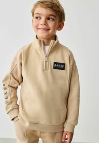 Beige lynlås sweatshirt med logo-patch, strukturerede ærmer og ribbede manchetter. Blødt materiale og afslappet pasform designet til komfort.