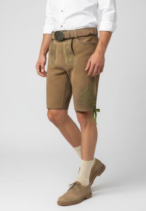 Braune Leder-Shorts mit grüner Stickerei, ausgestattet mit Seitentaschen, einem Gürtel und dekorativen Schnürungen am Saum, getragen mit strukturierten Kniehohsocken.