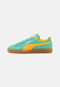 Adidași verzi din suede cu o dunga galbenă pe lateral, concepuți cu un finisaj texturat, având o talpă din cauciuc și detalii cu dungi pe limbă.