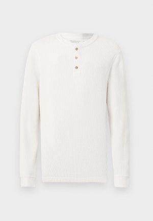 Maglietta bianca a maniche lunghe con bordo a coste, scollo rotondo e tre bottoni frontali, su sfondo uniforme.