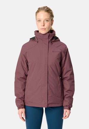 Vrouw draagt een waterdichte mauve jas met een hoge kraag en capuchon, staand tegen een effen lichte achtergrond.