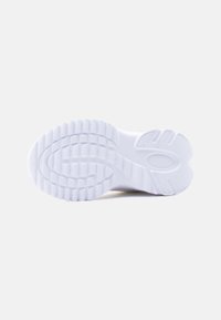 Λευκό πέλμα αθλητικού παπουτσιού με υφασμένα αυλάκια και σχέδια για καλύτερη πρόσφυση, φωτογραφημένο από κάτω σε απλό φόντο.