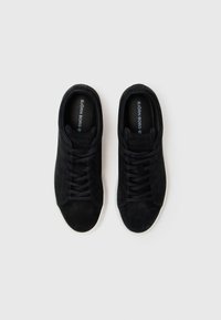 Sneakers negri din suede cu vârf neted, corp texturat și talpă din cauciuc alb. Au șireturi negre și o branț cu logo.