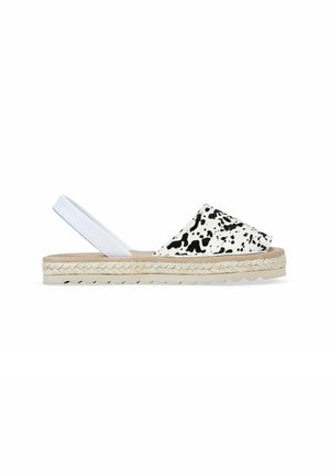 Espadrille tipo slingback con parte superior de textil a rayas blancas y negras, suela envuelta en yute, media suela beige y suela exterior de goma blanca.
