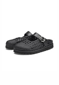 Zoccoli intrecciati neri con superficie testurizzata, cinturino in pelle e dettaglio con fibbia in metallo, dotati di una spessa suola in gomma per una migliore aderenza.