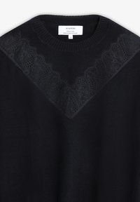 Suéter negro de tela suave, con un patrón de encaje en el yugo. Cuello redondo y bordes acanalados. Etiqueta de cuidado adjunta en el interior del cuello.