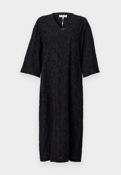 Robe noire avec un décolleté en V et des manches trois-quarts, confectionnée dans un tissu texturé à motif floral. Silhouette longue et ample.