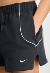 Černé šortky Nike s tkaničkou v pase, světlomodrými lemy, bočními kapsami a bílým logem na lemu. Měkká textilie.