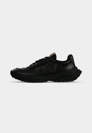 Baskets basses en cuir noir à surface texturée, lacets à l'avant, semelle épaisse et talon légèrement surélevé, vues de profil sur fond blanc.