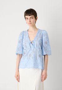 Lichtblauwe blouse met fladdermouwen, gaatjespatronen, een v-hals en een gegolfde zoom. Gemaakt van zachte, gestructureerde stof.